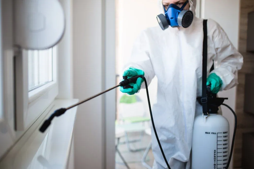 TCB technician performing indoor pest control treatment